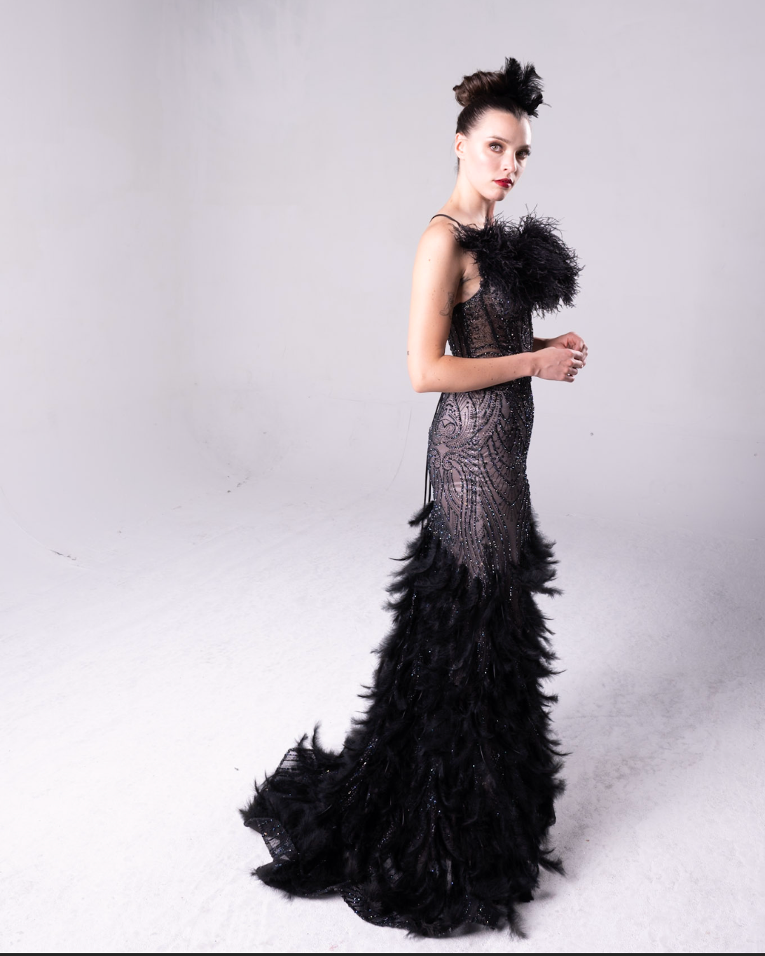 Beaded gown with fleah colored lining, feather details on the bodice and all over the maermaid style train.