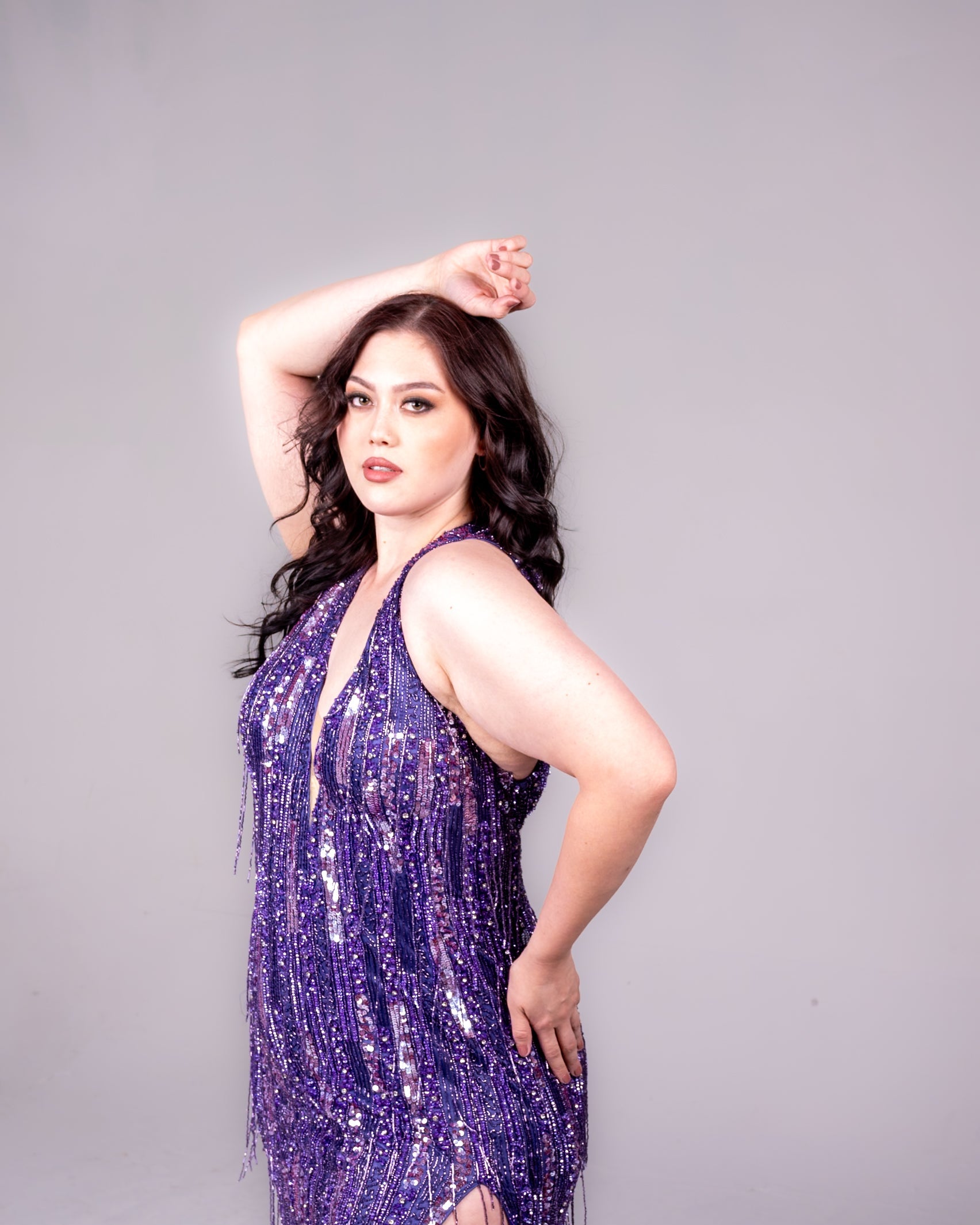purple beaded gown with sequin and fringe silver details. High split, with a low open back. Halter neckline. 