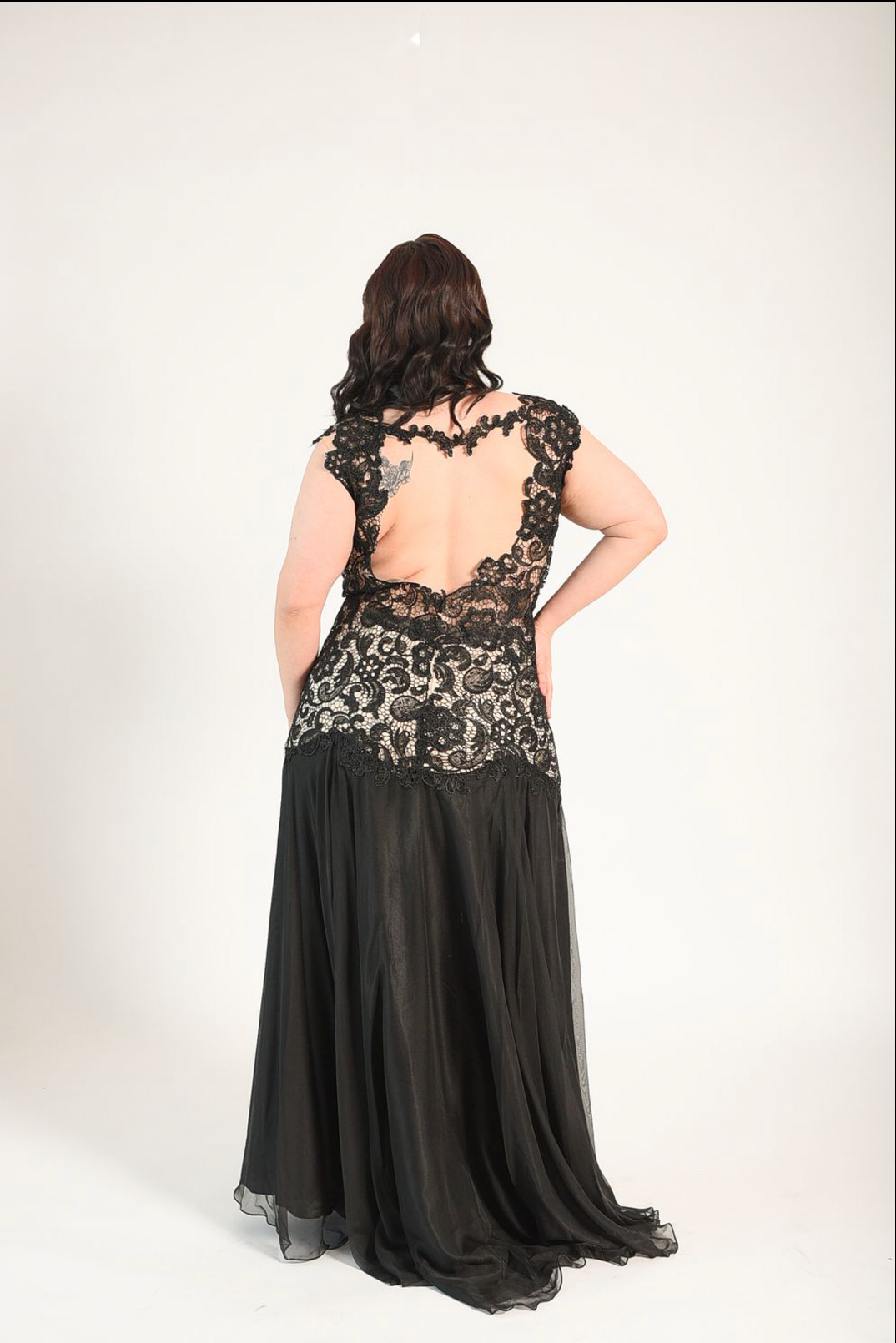 Black gown in a lace fabric, sheer cutouts on the waist, with a backless design. High split. 