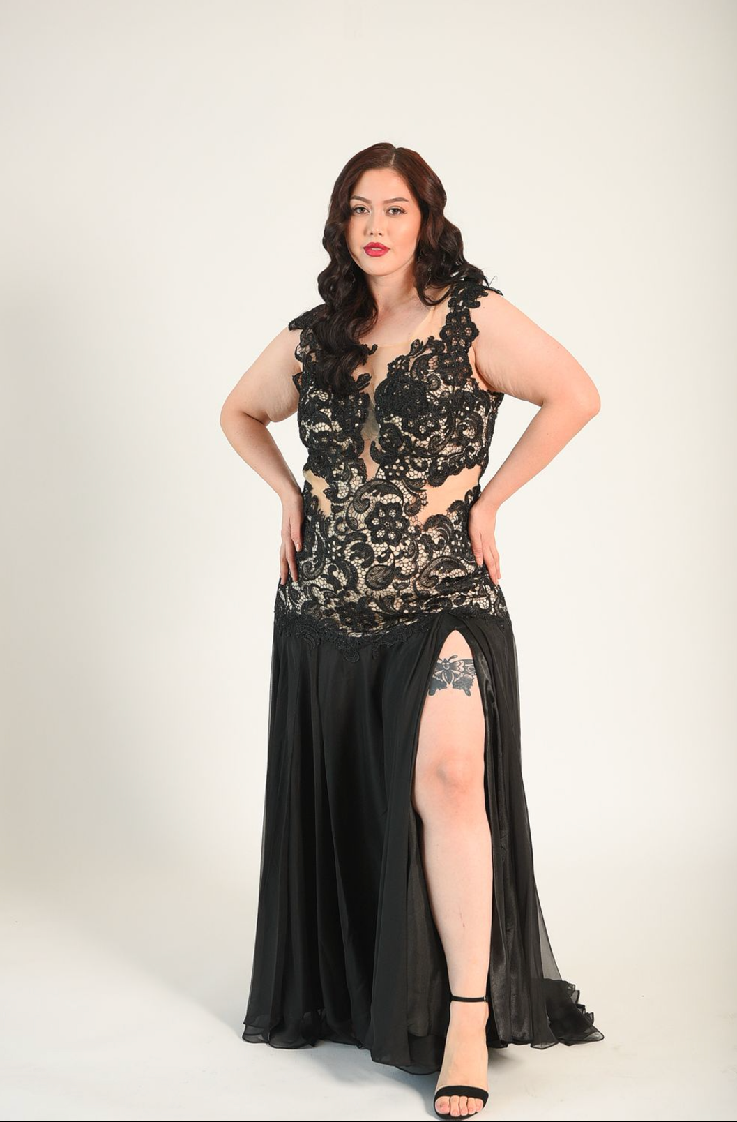 Black gown in a lace fabric, sheer cutouts on the waist, with a backless design. High split. 