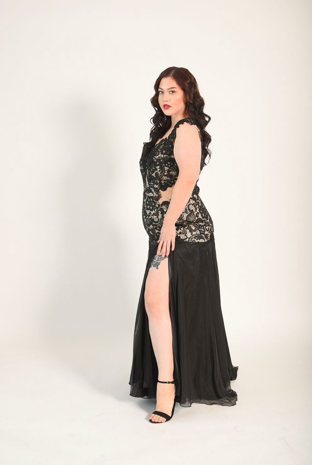 Black gown in a lace fabric, sheer cutouts on the waist, with a backless design. High split. 