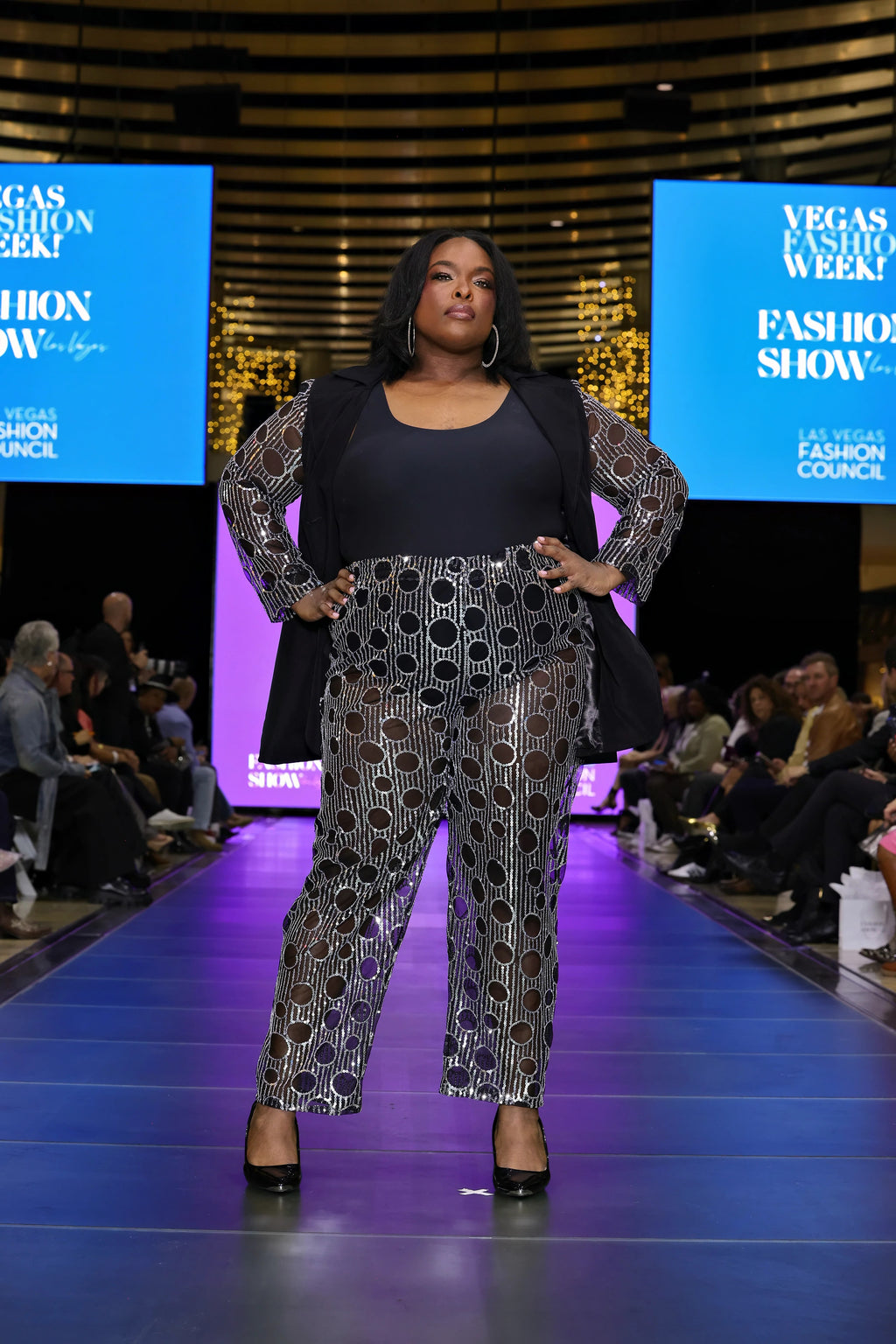 A model posed on the runway, standing strong in a sequin pantsuit. 