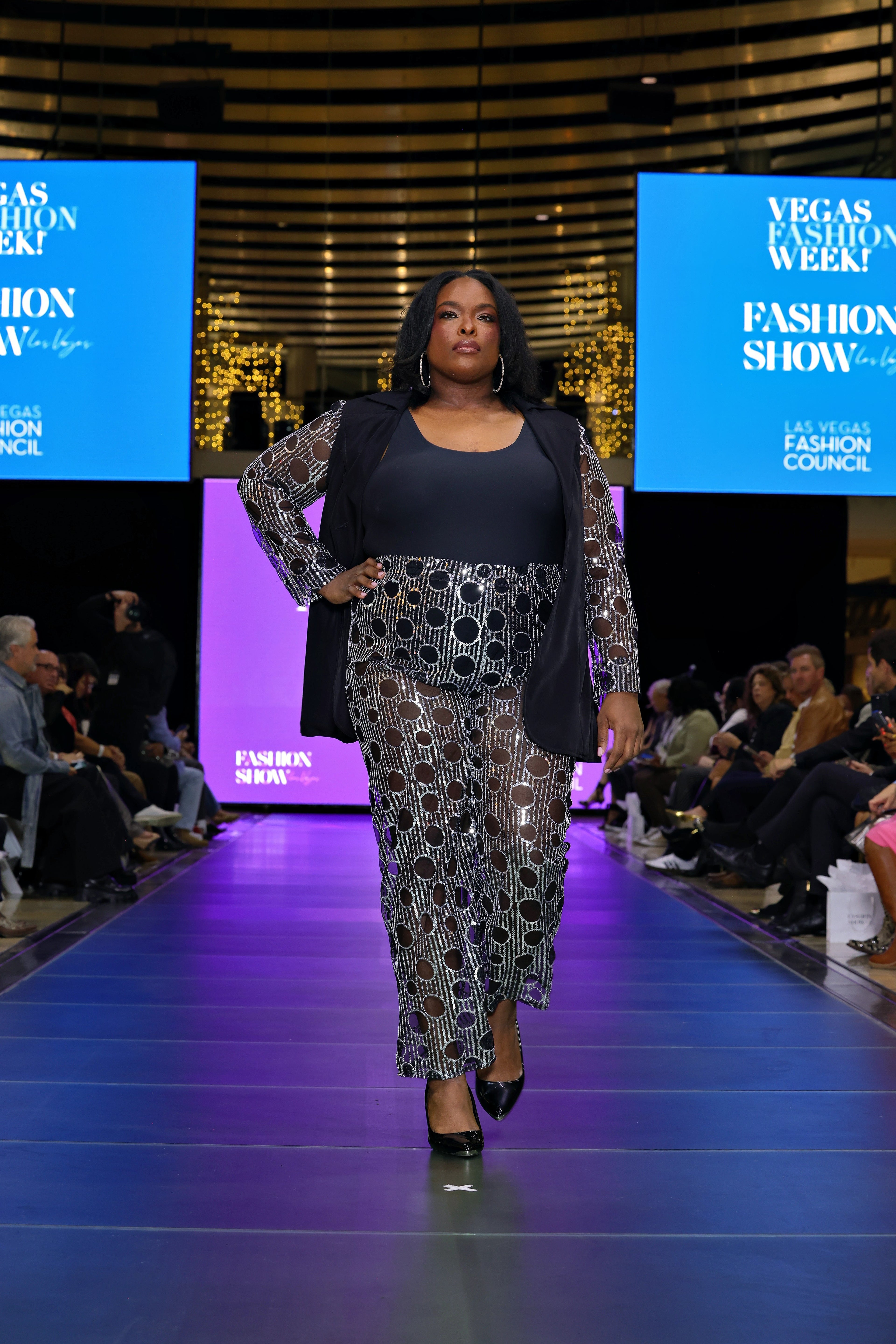 A woman walking on the runway in a sequin suit 