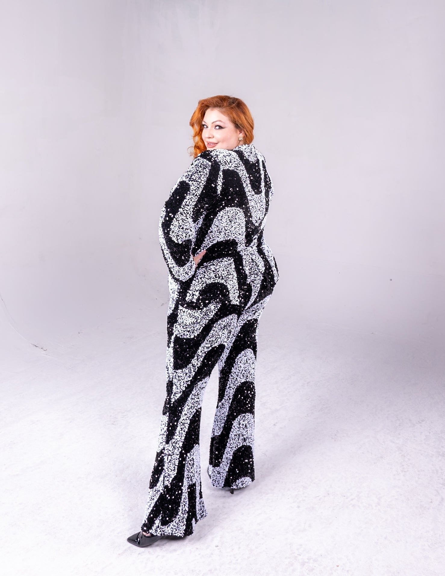 black and white sequin fabric, with swirl pattern. Blazer is a tailored fitted style, and the pants are flared.