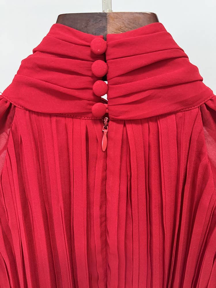 Red pleated dress with button details on a hanger against a white background
