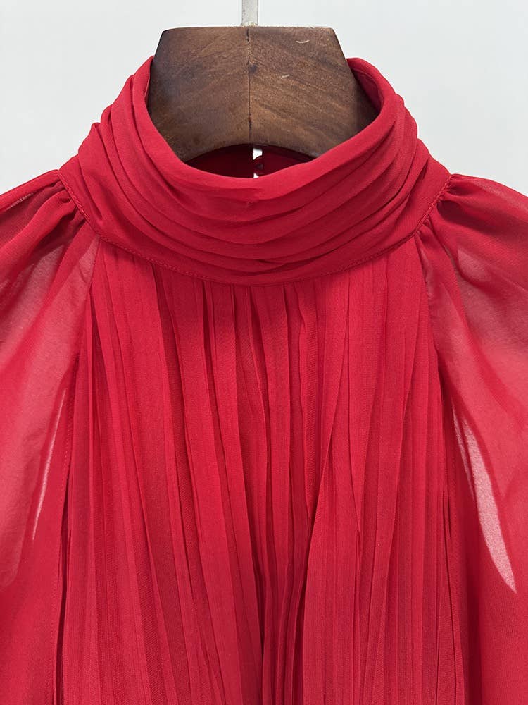 Red pleated gown on a wooden hanger against a white background