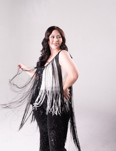 sequin fringe jumpsuit with color block detail. One side is all black, and a portion of it is white. Fringe hangs down from the neckline around the bodice of the jumpsuit