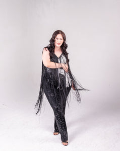 sequin fringe jumpsuit with color block detail. One side is all black, and a portion of it is white. Fringe hangs down from the neckline around the bodice of the jumpsuit