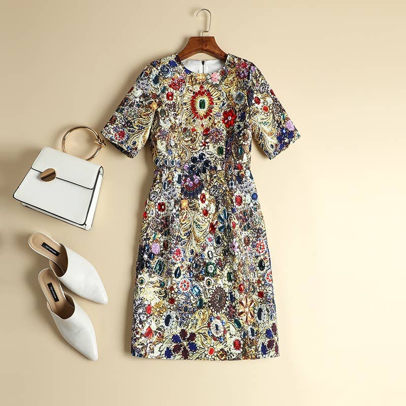 Gemstone pattern dress on a hanger with white shoes and a white handbag on a beige background