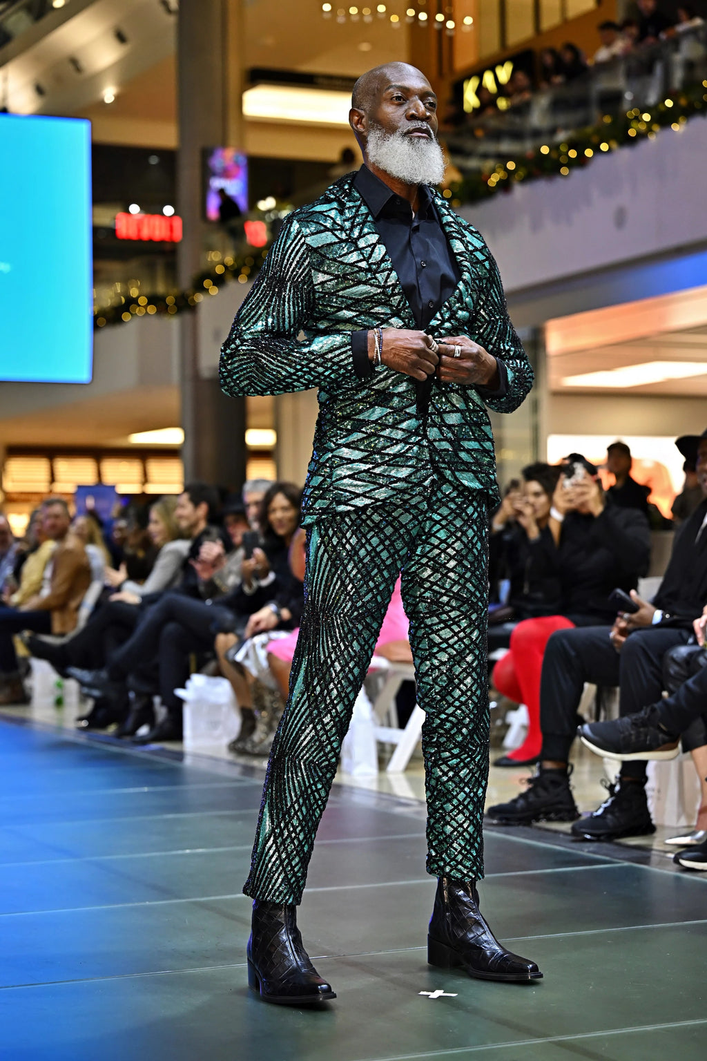 A person wearing a green patterned outfit in a fashion show setting