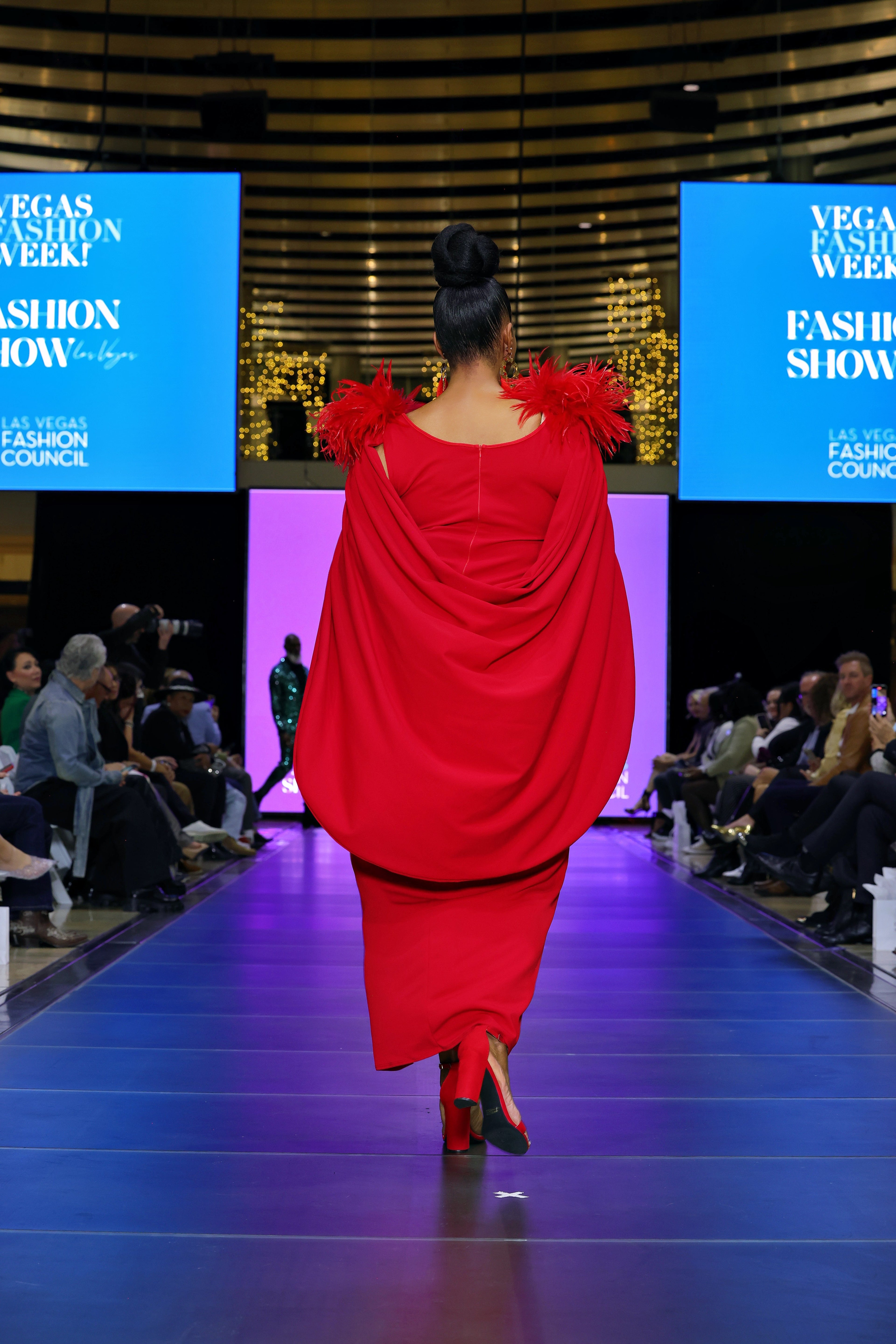 A woman in a red dress walking on a runway.