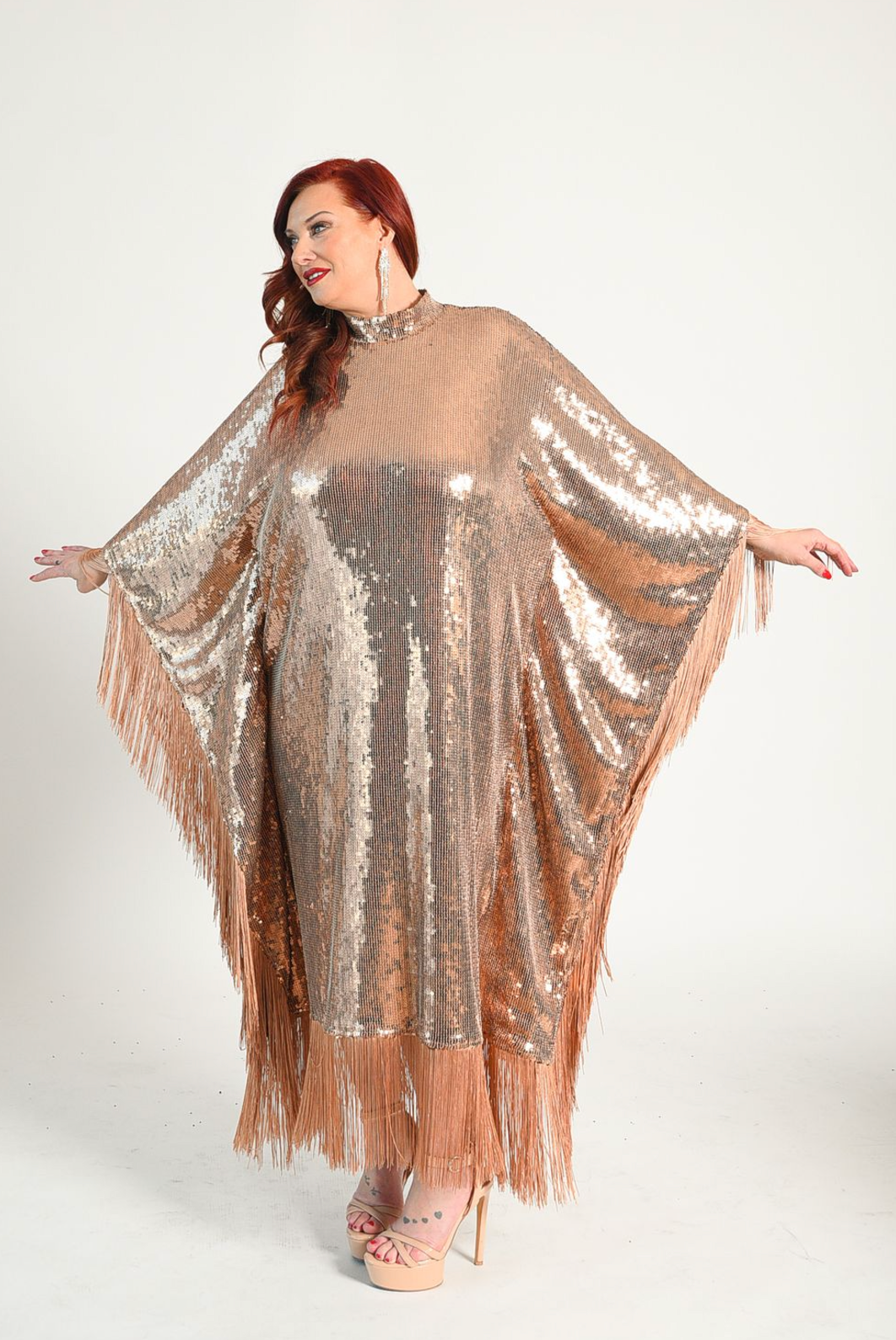 Sequin caftan style dress with fringe attached at the hem of the sleeves and bottom of the dress. Button closure at the neck. 