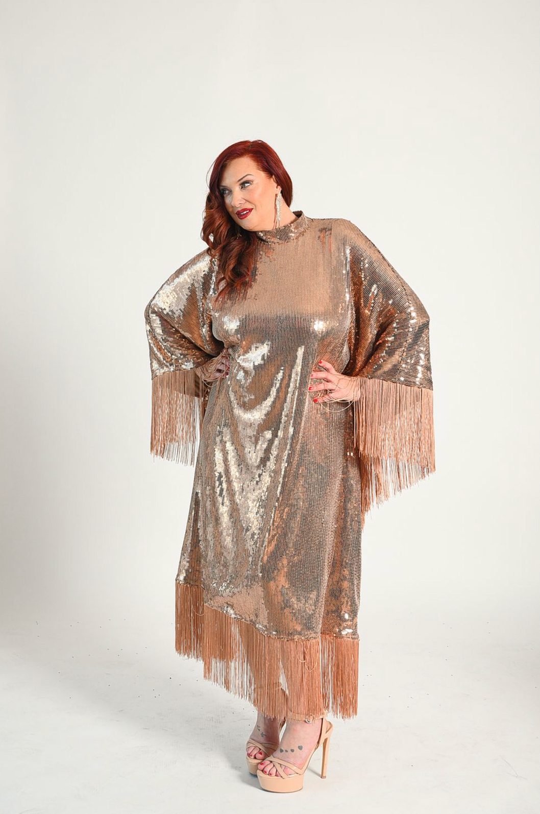 Sequin caftan style dress with fringe attached at the hem of the sleeves and bottom of the dress. Button closure at the neck. 