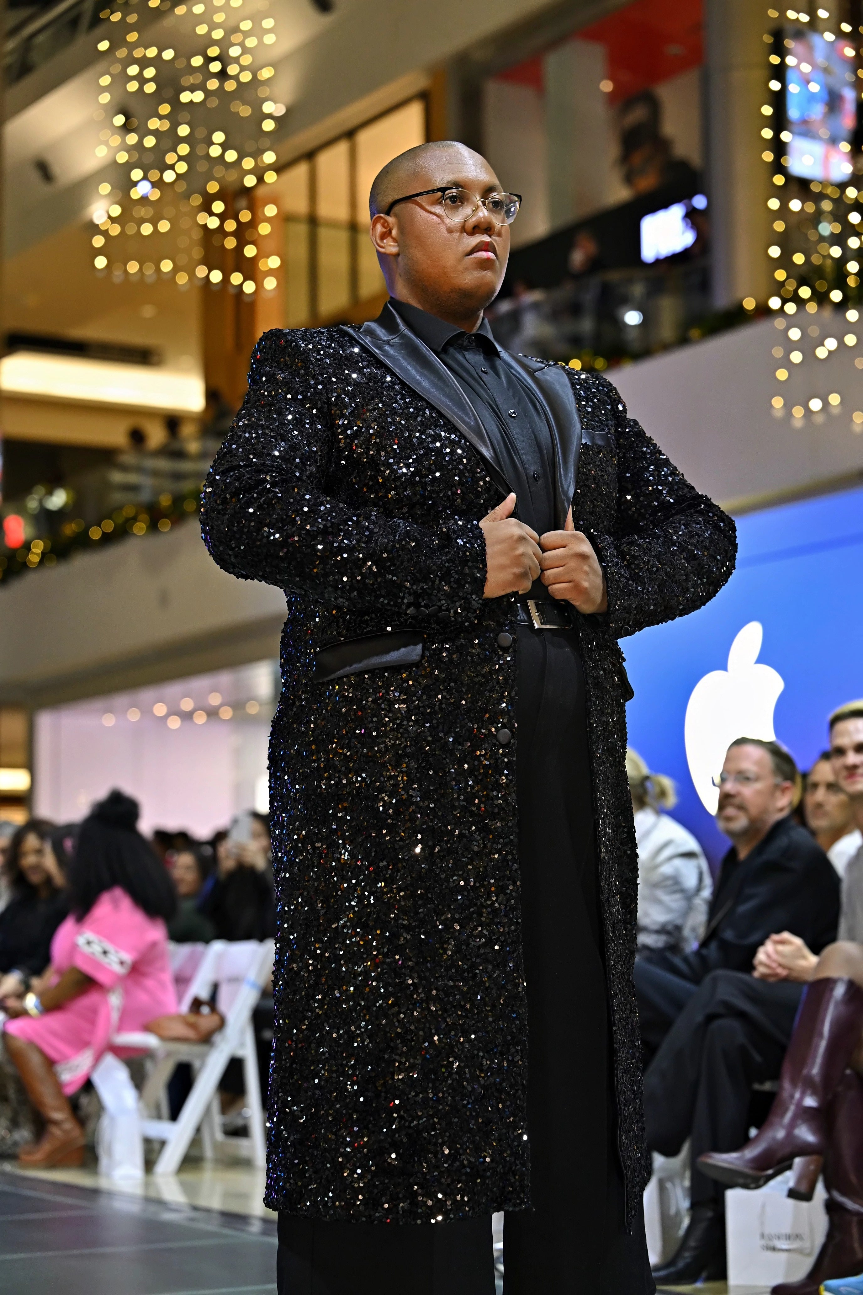 A model wearing a black sequined coat on a runway
