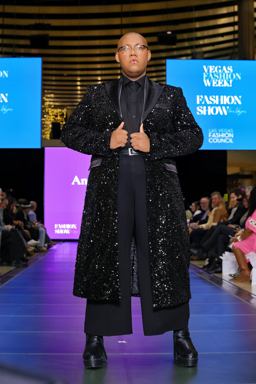 A model wearing a black sequin trench coat on the runway 
