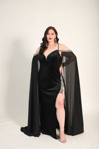 Formal gown with a high split adorned with crystal details. Cape sleeves. In a stretch velvet material. 
