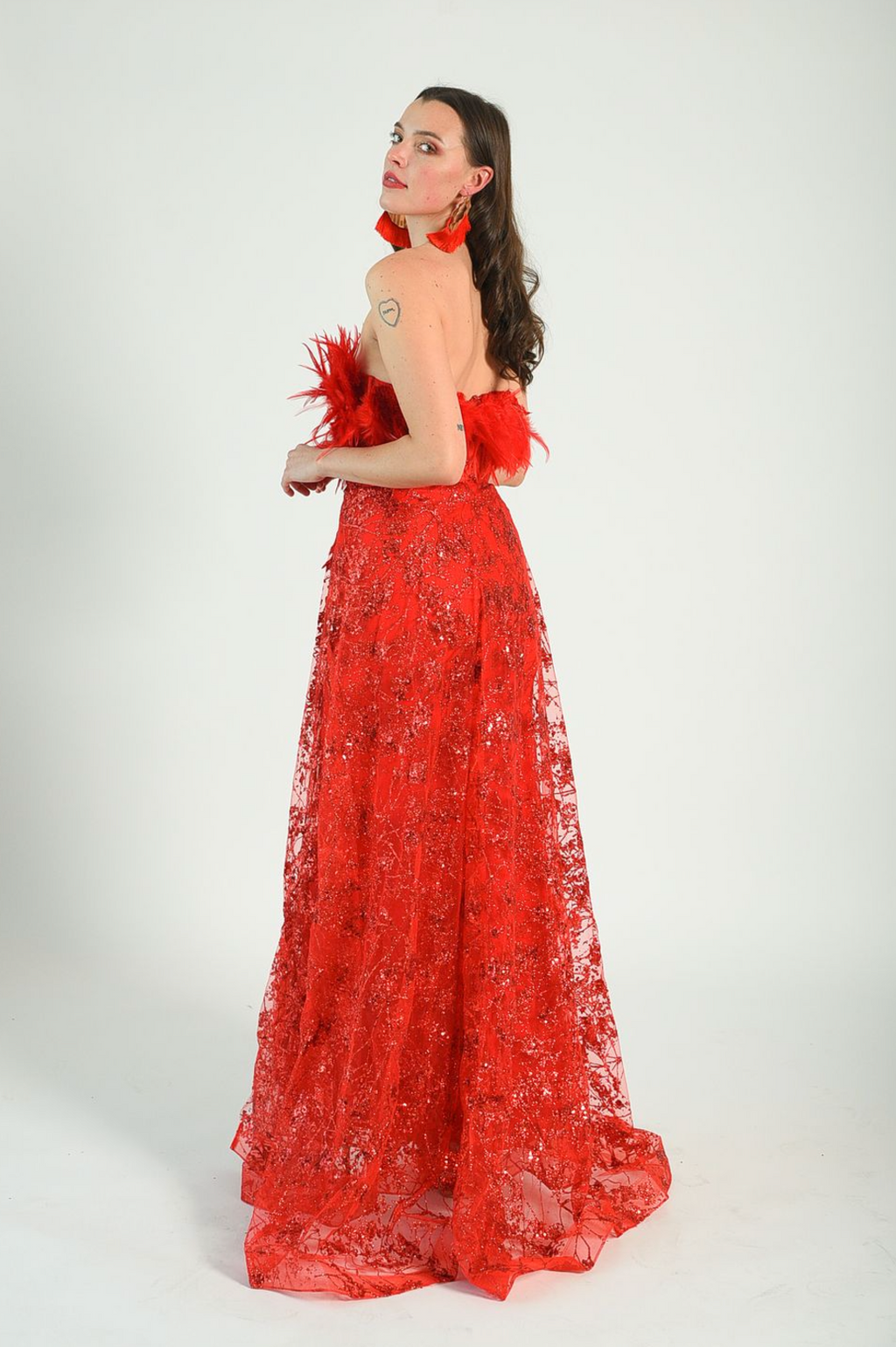 Red sequin gown with an overskirt, feather details across the bust, fitted gown style. Back zipper. 