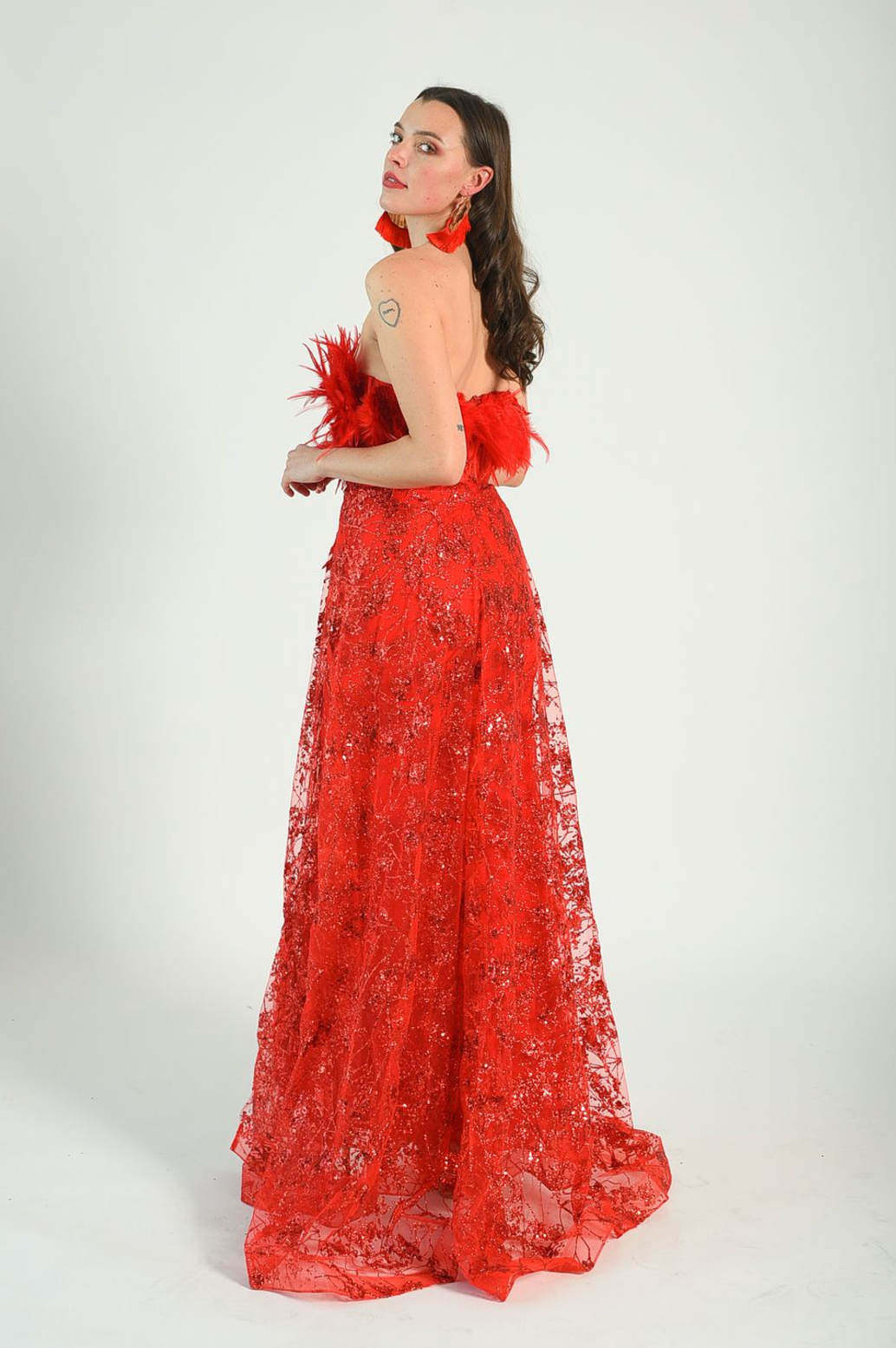 Red sequin gown with an overskirt, feather details across the bust, fitted gown style. Back zipper. 