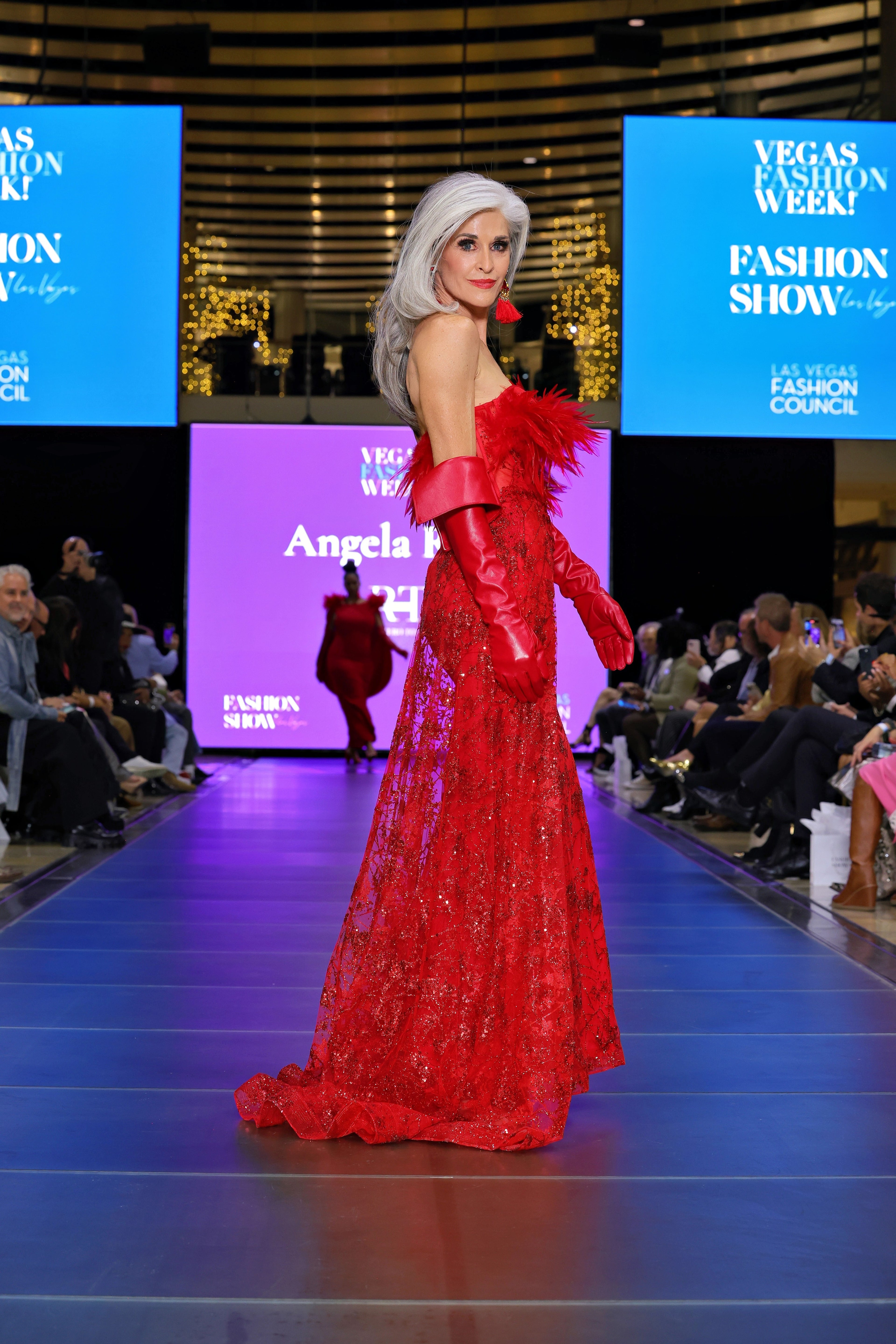 A model wearing a red dress on a runway 