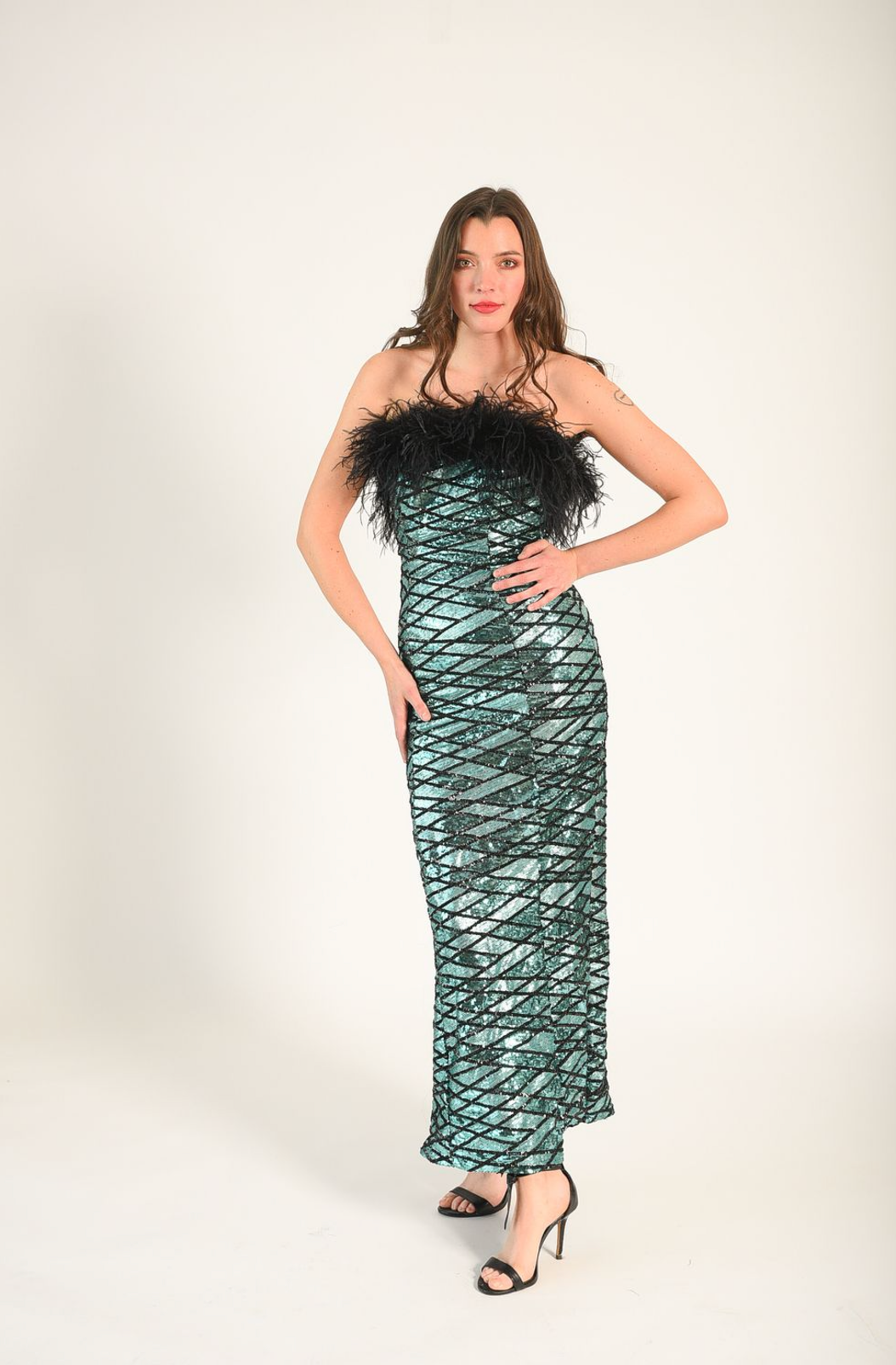 Blue/green sequin fabric with black zig-zag lines across each other. Black feathers adorn the bodice. The dress is strapless. 